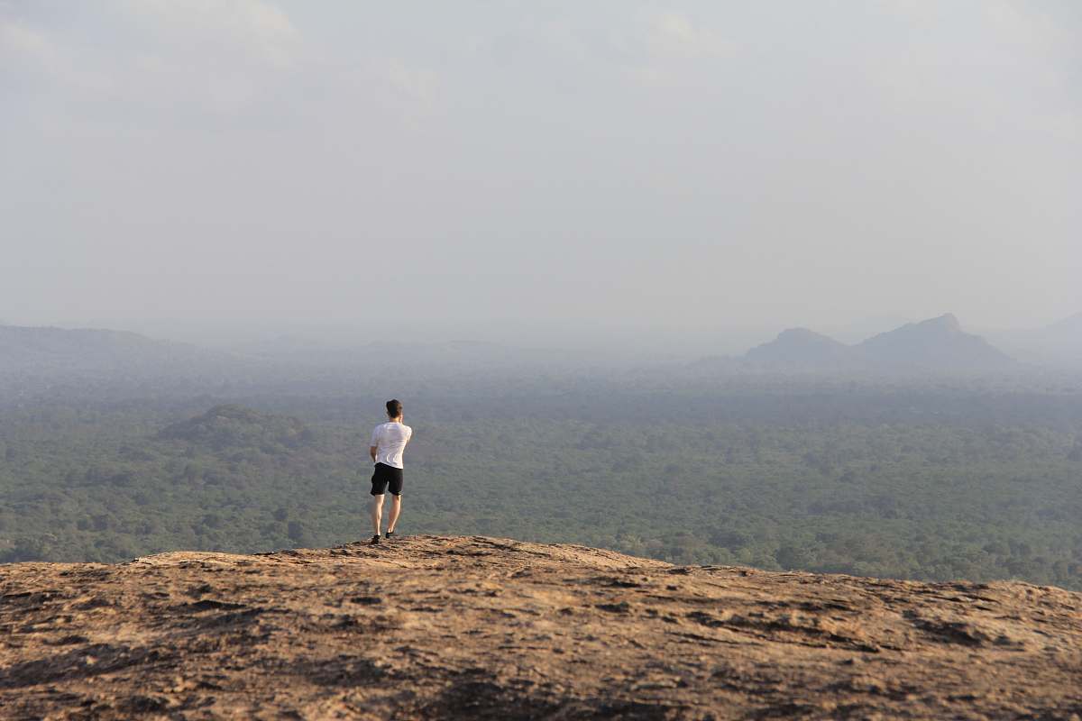 pidurangala rock man in white T-shirt standing on mountain during day time sigiriya